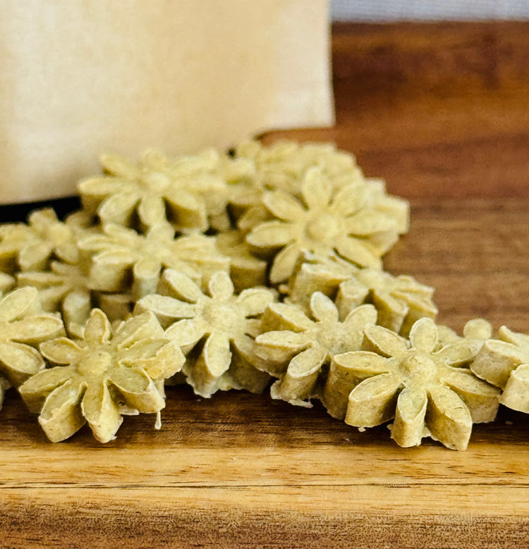 Flower-shaped rabbit treats on a wooden surface with a brown kraft bag in the background