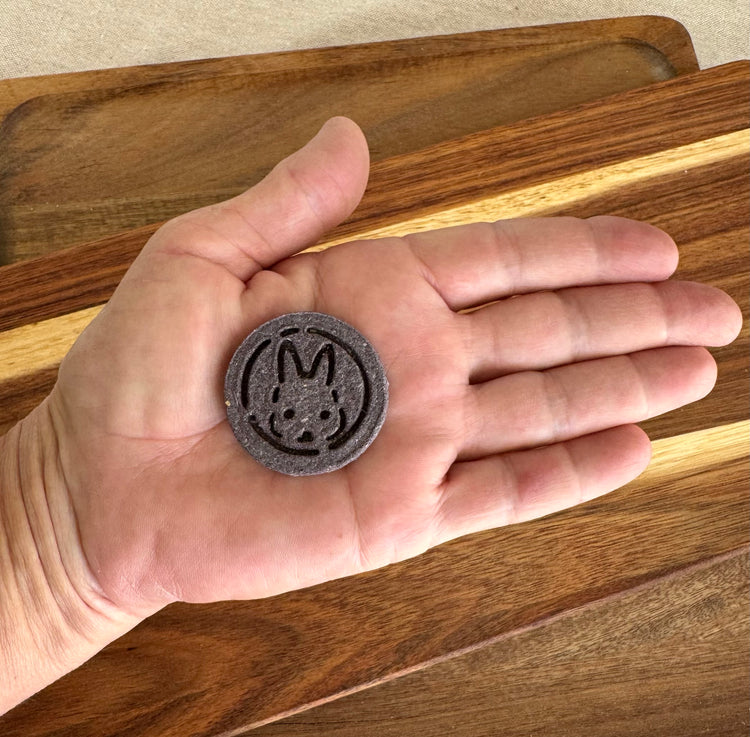 Hand holding a Purple botanical rabbit biscuit with blueberry antioxidants from BunBun & Co to show scale