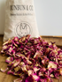 Dried pink rose petals on a wooden surface with a &
