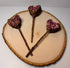 Heart-shaped rabbit forage pops with dried rose petals, botanicals  and a peach wood chew stick handles displayed on natural wood slice