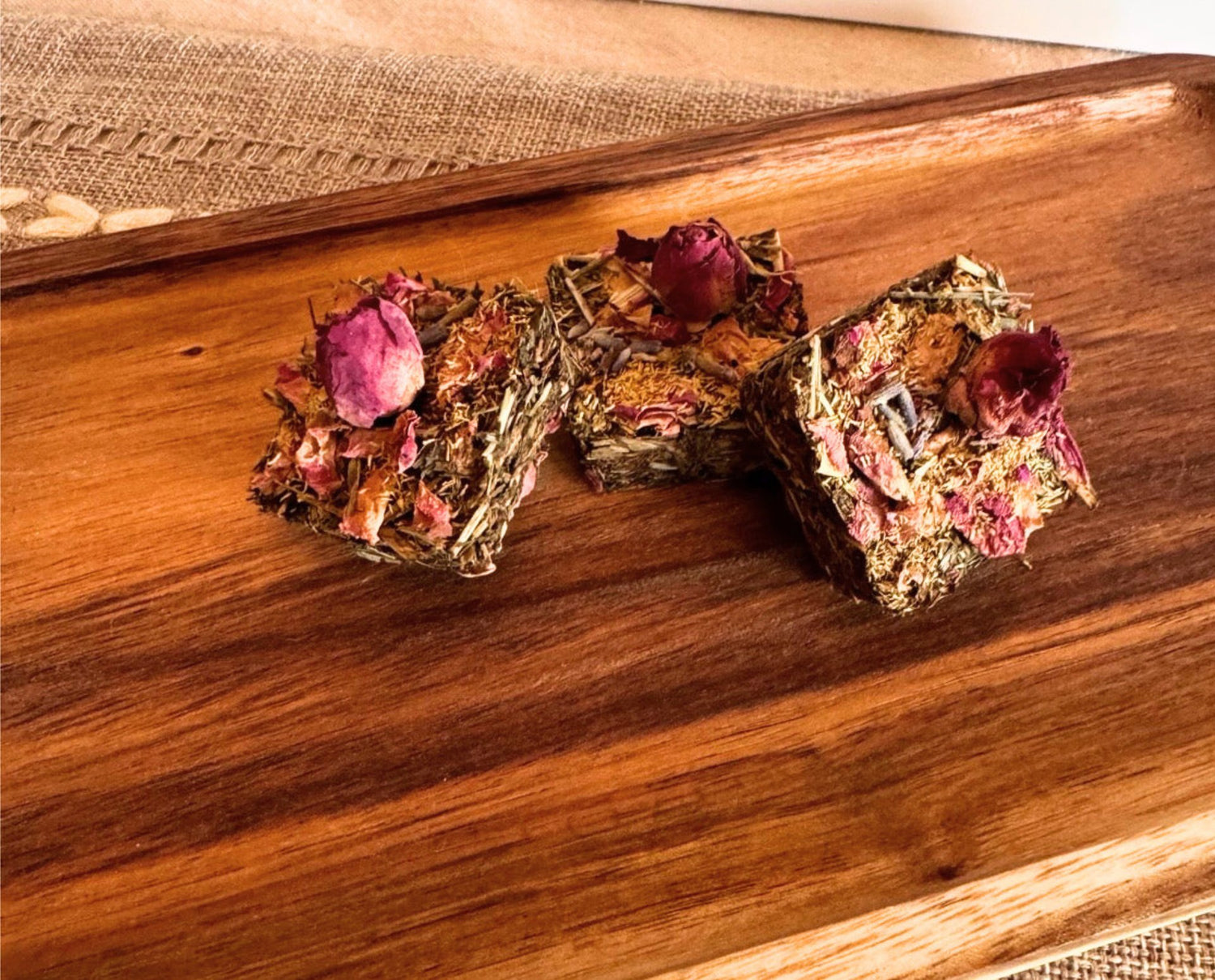 Botanical forage bars for small pets styled on neutral linen with natural wood board and dried floral ingredients