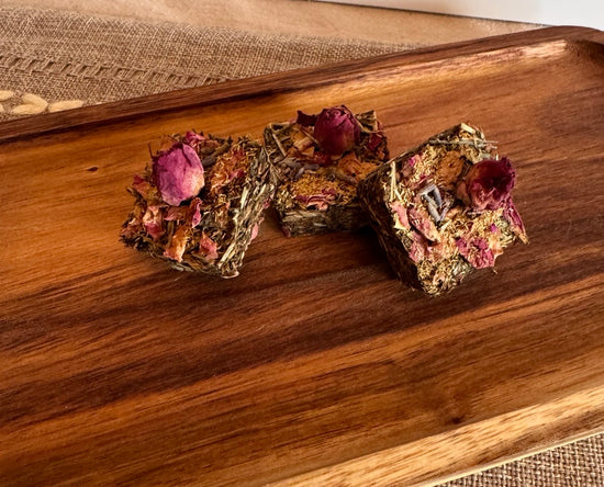 Botanical forage bars for small pets styled on neutral linen with natural wood board and dried floral ingredients
