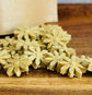 Flower-shaped rabbit treats on a wooden surface with a brown kraft bag in the background