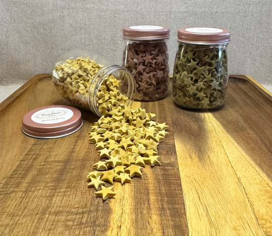  Yellow and green star-shaped rabbit treats spilling from clear apothecary jars onto wooden tray
