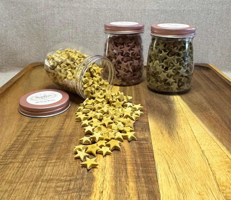  Yellow and green star-shaped rabbit treats spilling from clear apothecary jars onto wooden tray