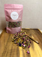 Rabbit forage blend with dried herbs and florals displayed in pink resealable mylar bag with loose blend and wooden scoop