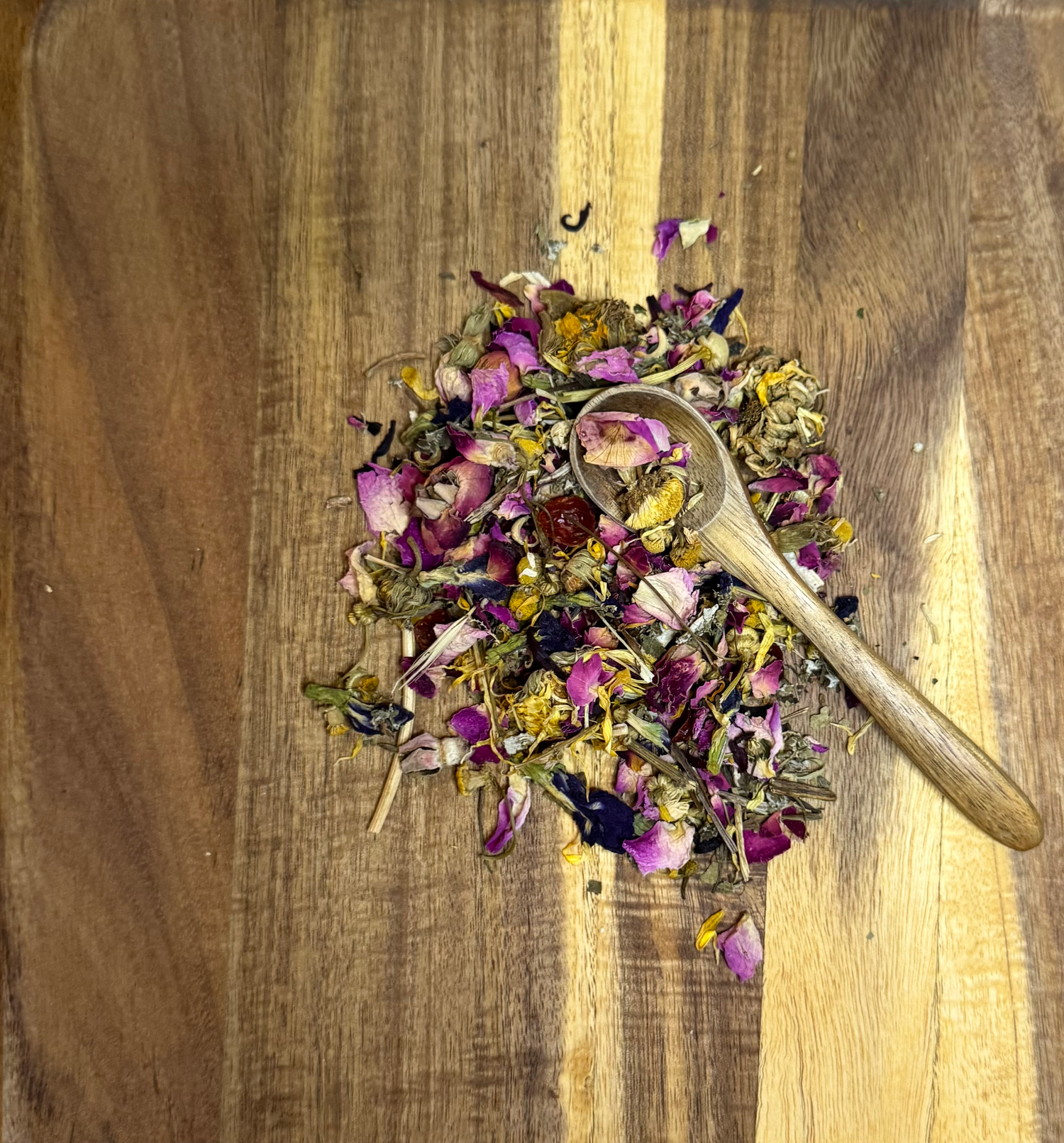 Mixed herbal and rose petal rabbit forage blend on wooden board with wooden scoop