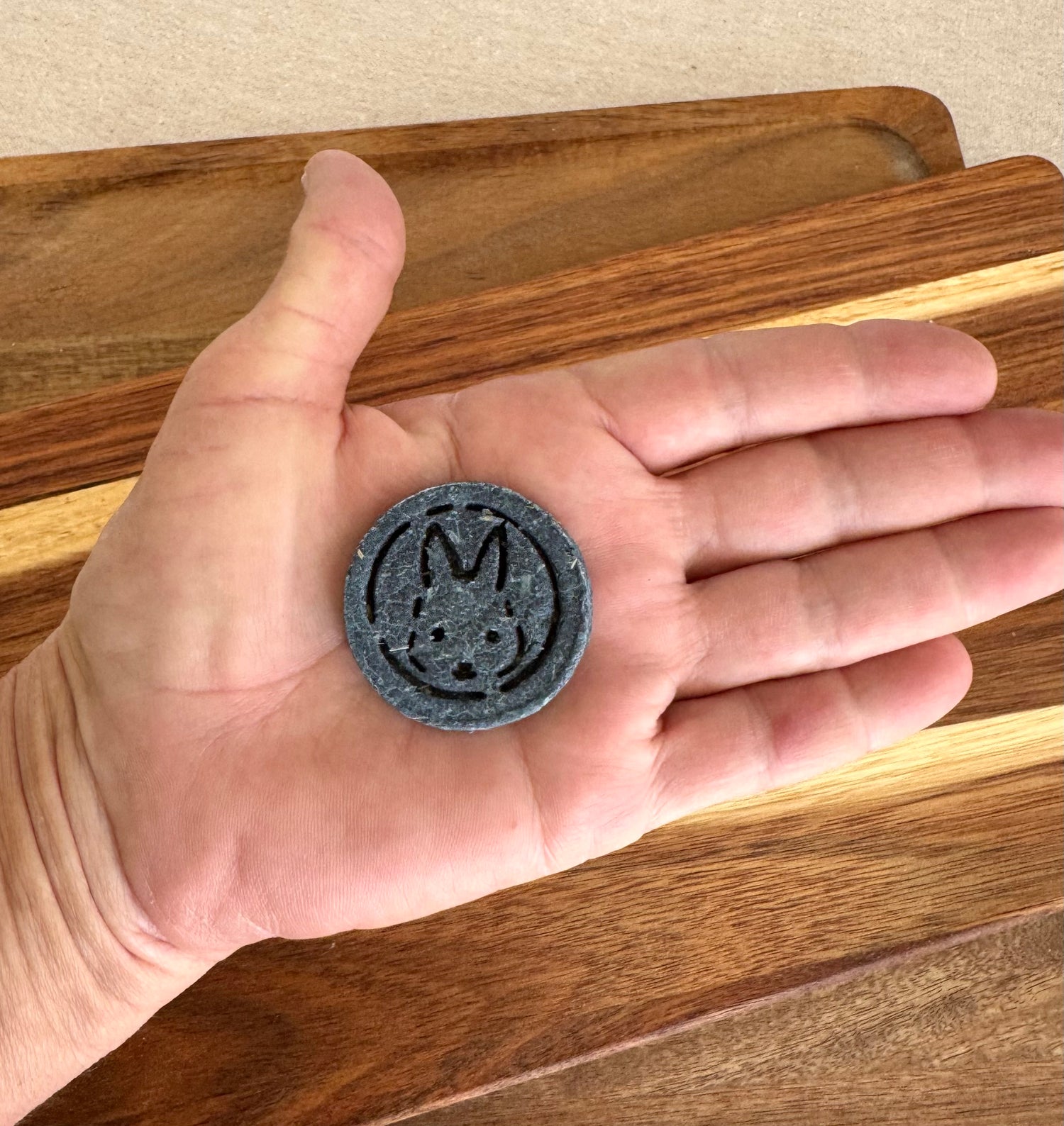 Hand holding Blue botanical rabbit biscuit for skin and coat support from BunBun & Co to show scale
