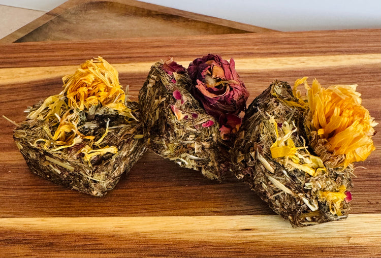 Botanical digestive forage bites for rabbits on a wooden board made with plantain, dandelion, and chamomile,calendula and rose buds