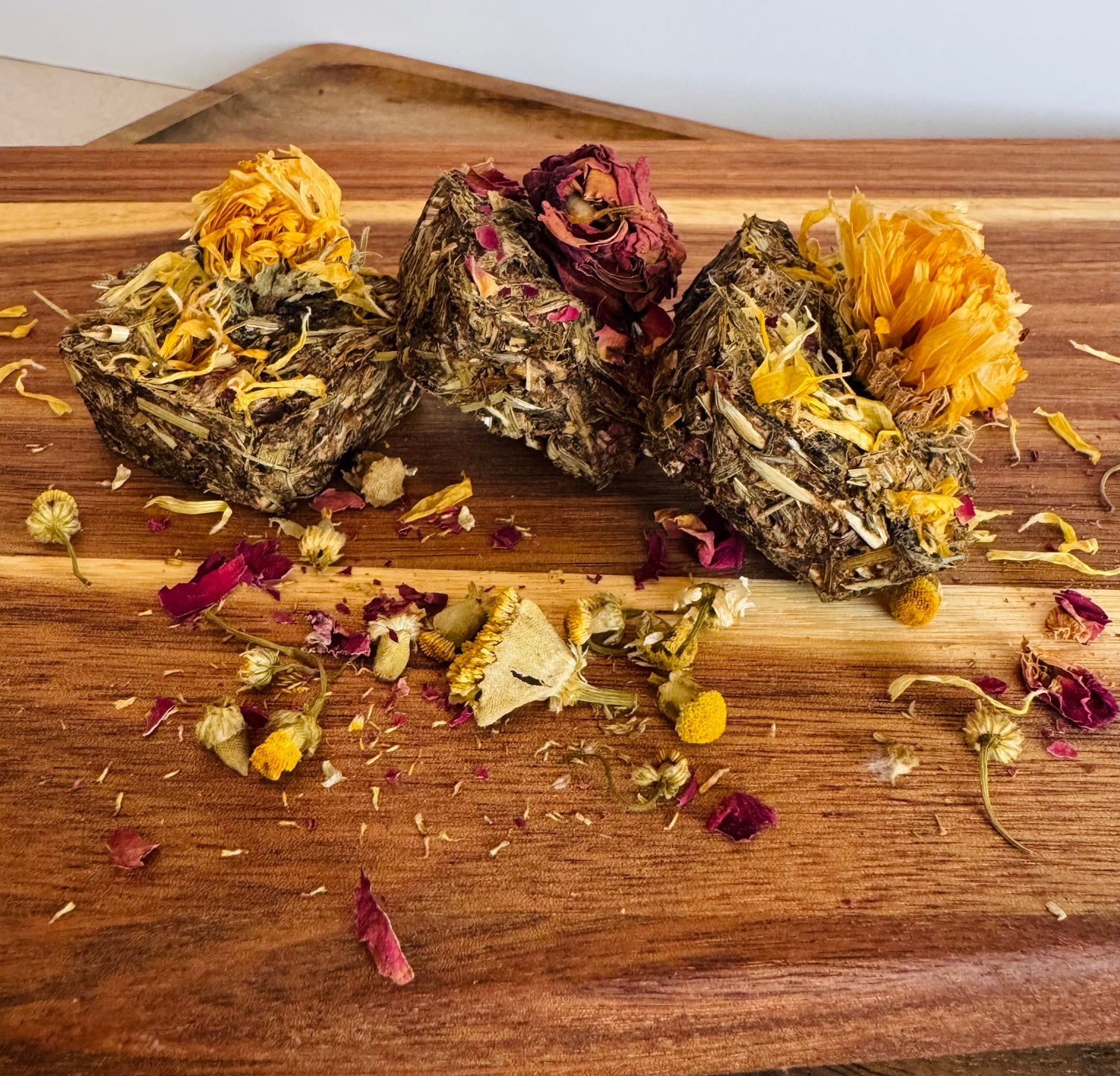 Botanical digestive forage bites for rabbits on a wooden board made with plantain, dandelion, and chamomile