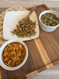 Two bowls of star-shaped rabbit treats on a wooden cutting board with a white plate and wooden spoon.