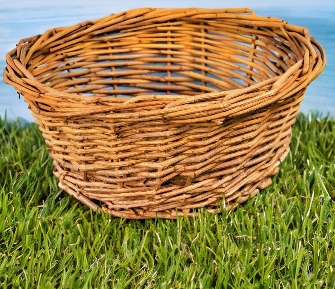 Woven willow basket resting on green grass with natural outdoor background