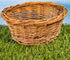 Woven willow basket resting on green grass with natural outdoor background