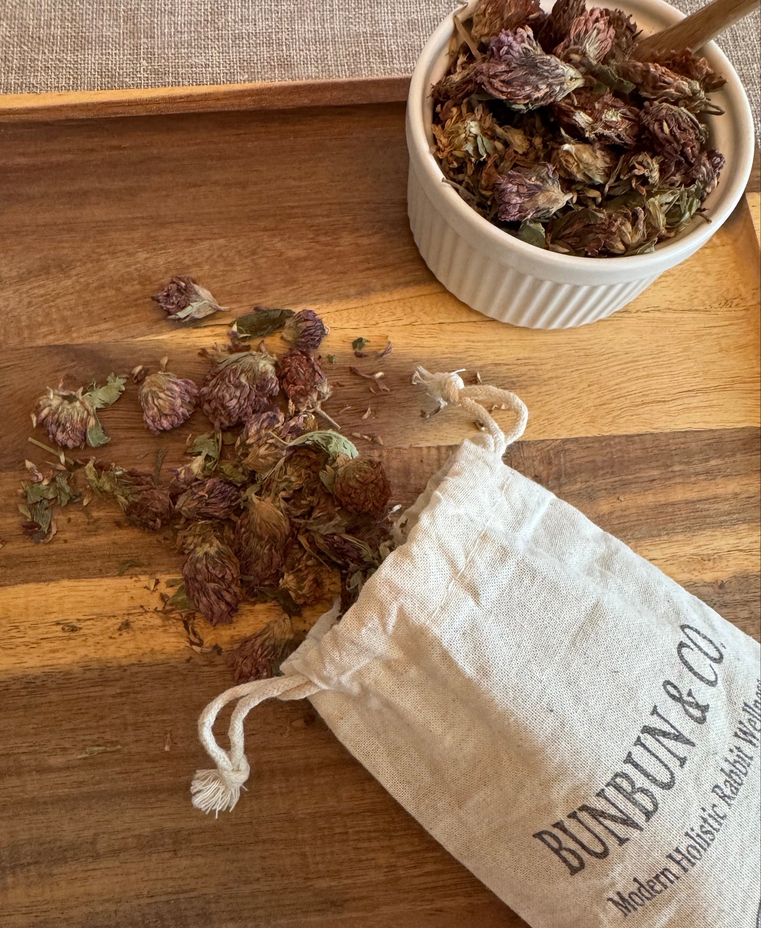 Dried red clover blossoms spilling out of a white cotton &