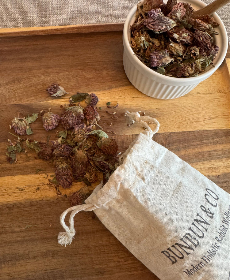 Dried red clover blossoms spilling out of a white cotton &