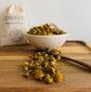 Dried  chamomile flowers in a white bowl on a wooden surface with a &
