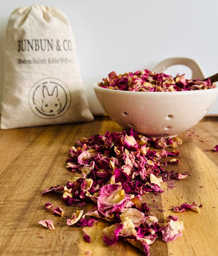 Dried pink rose petals on a wooden surface with a &