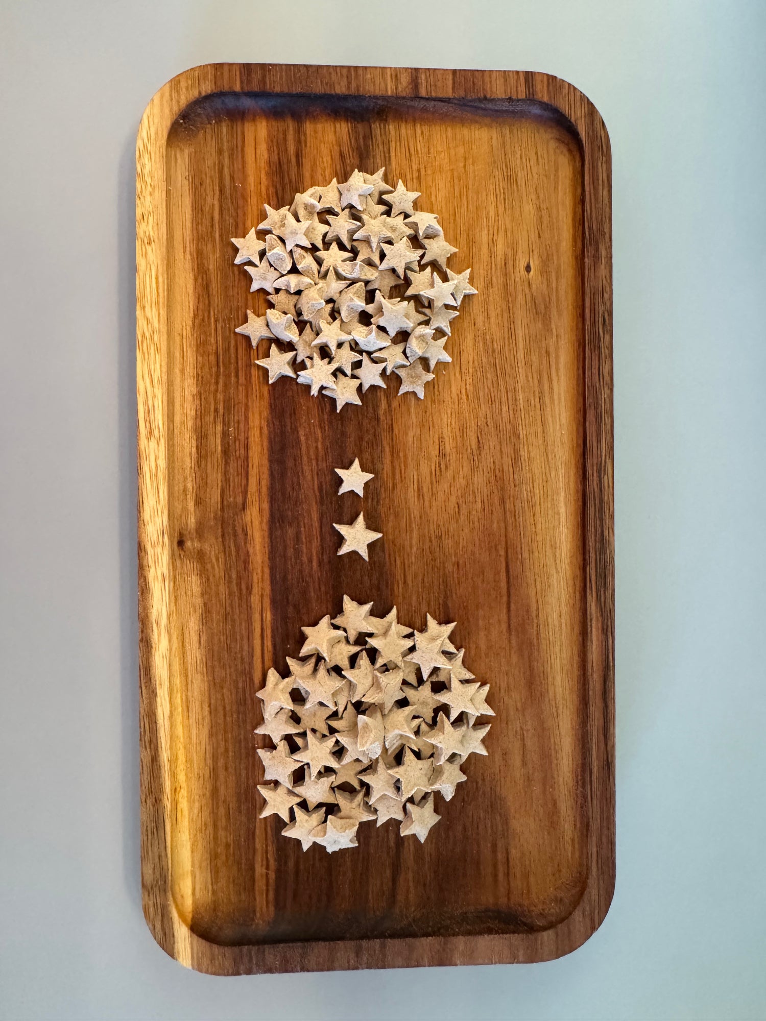 Cream colored Star shaped rabbit treats laying scattered on a wooden tray