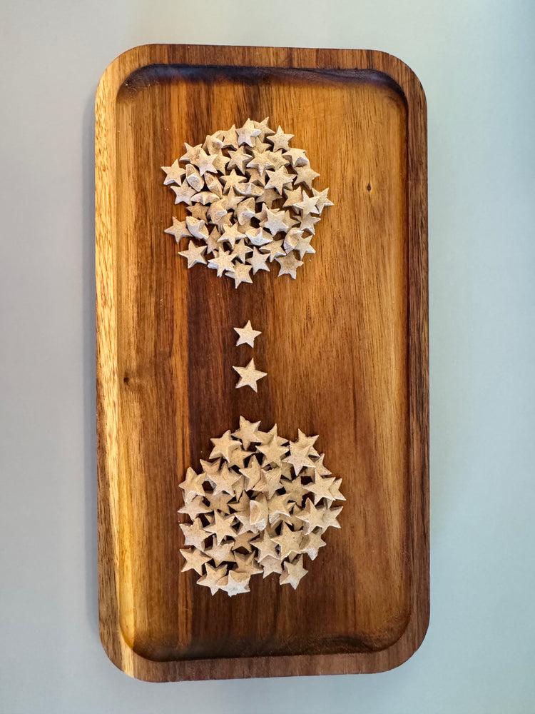 Cream colored Star shaped rabbit treats laying scattered on a wooden tray